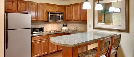 Una cocina con gabinetes de madera, un refrigerador de acero inoxidable, un microondas, una estufa y un lavamanos.