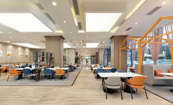 A spacious indoor dining area with high ceilings, recessed lighting, and large windows.