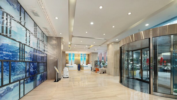 A modern hotel lobby with a reception desk, seating area, and a glass wall offering a view of the street. - Holiday Inn Express Chengdu Wuhou by IHG (Chengdu)