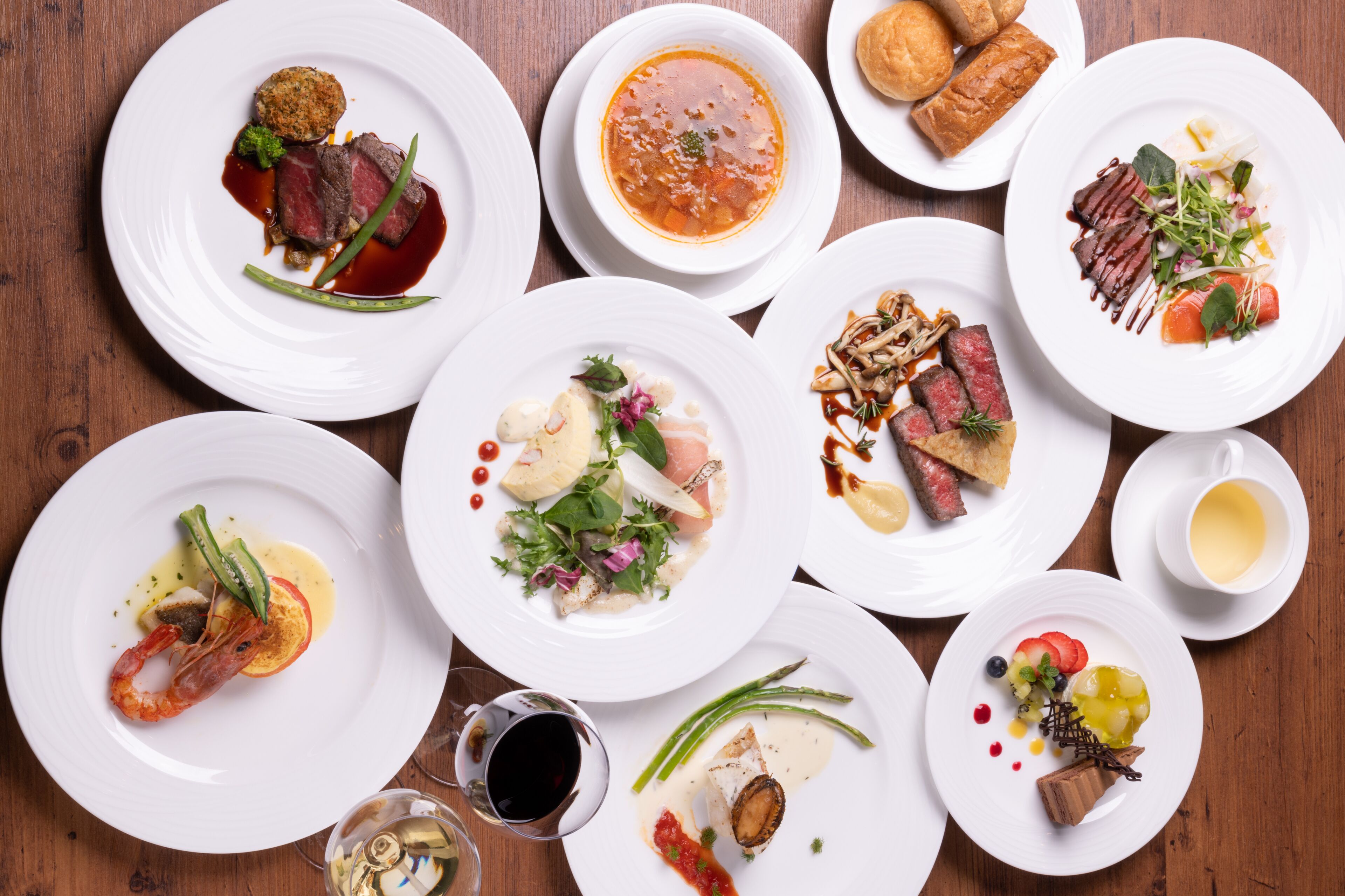 A variety of dishes on white plates arranged on a wooden table.