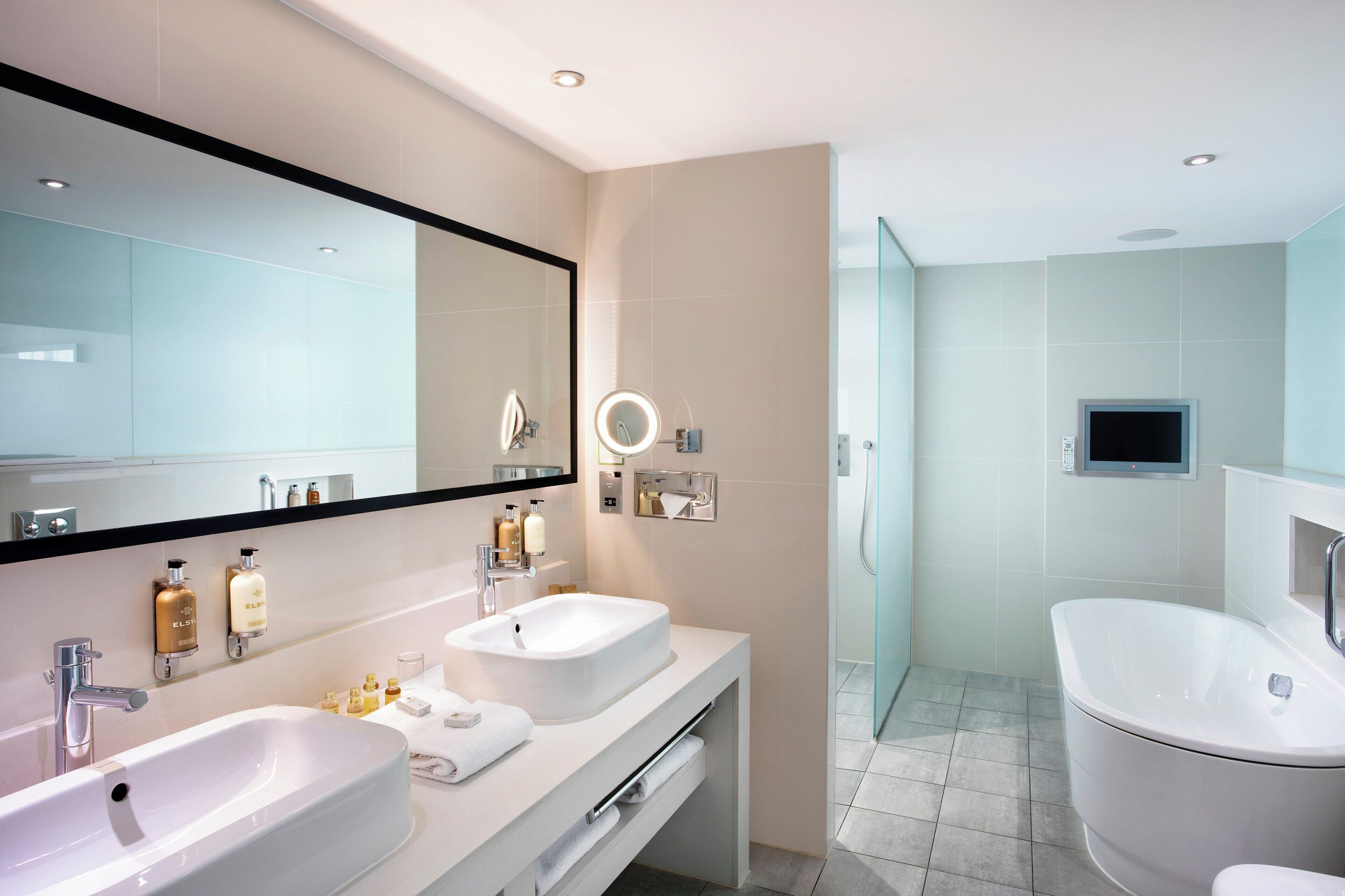 Une salle de bain moderne avec deux lavabos, un grand miroir et un espace douche.