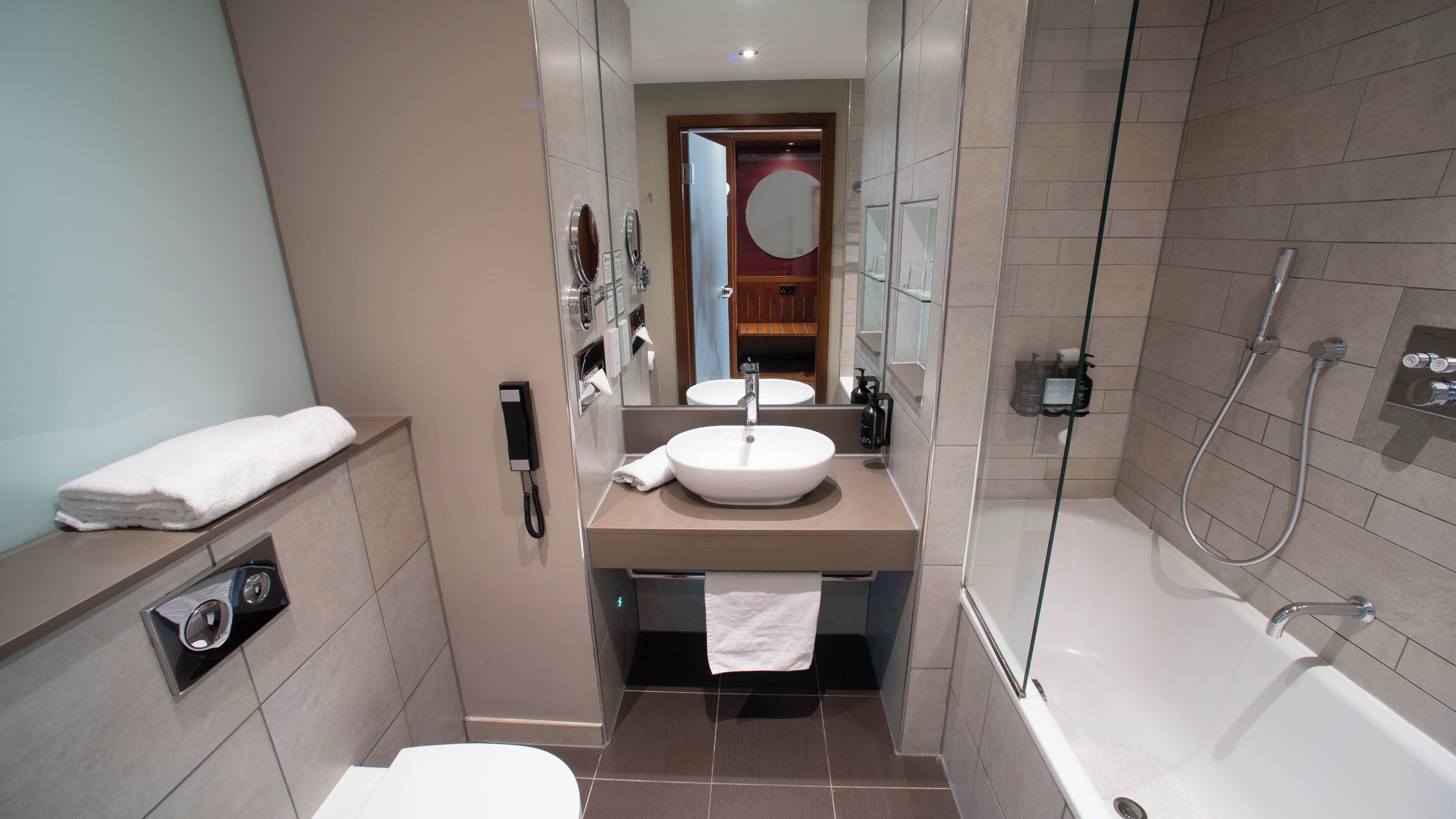 A modern bathroom with a sink, mirror, and shower.