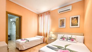 A hotel room with two beds, a bathroom, and an air conditioning unit. - Luz Madrid Rooms (Madrid)