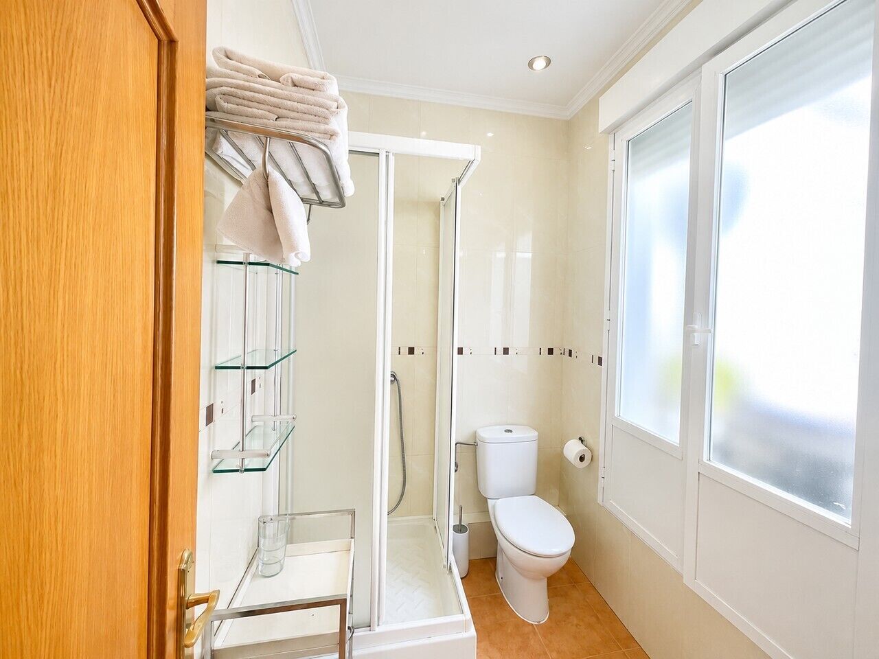 Un baño con cabina de ducha de vidrio, inodoro y un perchero para toallas.