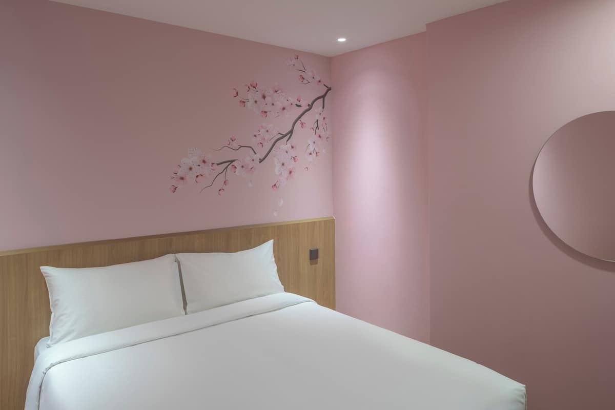 Cama bem arrumada com lençóis brancos em quarto com paredes rosa e cabeceira de madeira.