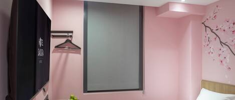 Habitación de hotel con dos camas, un escritorio con cafetera, televisión y estante en la pared.