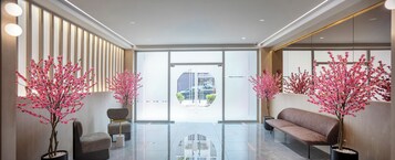 Un lobby moderno con mostrador de recepción, zona de estar y ventanas amplias.