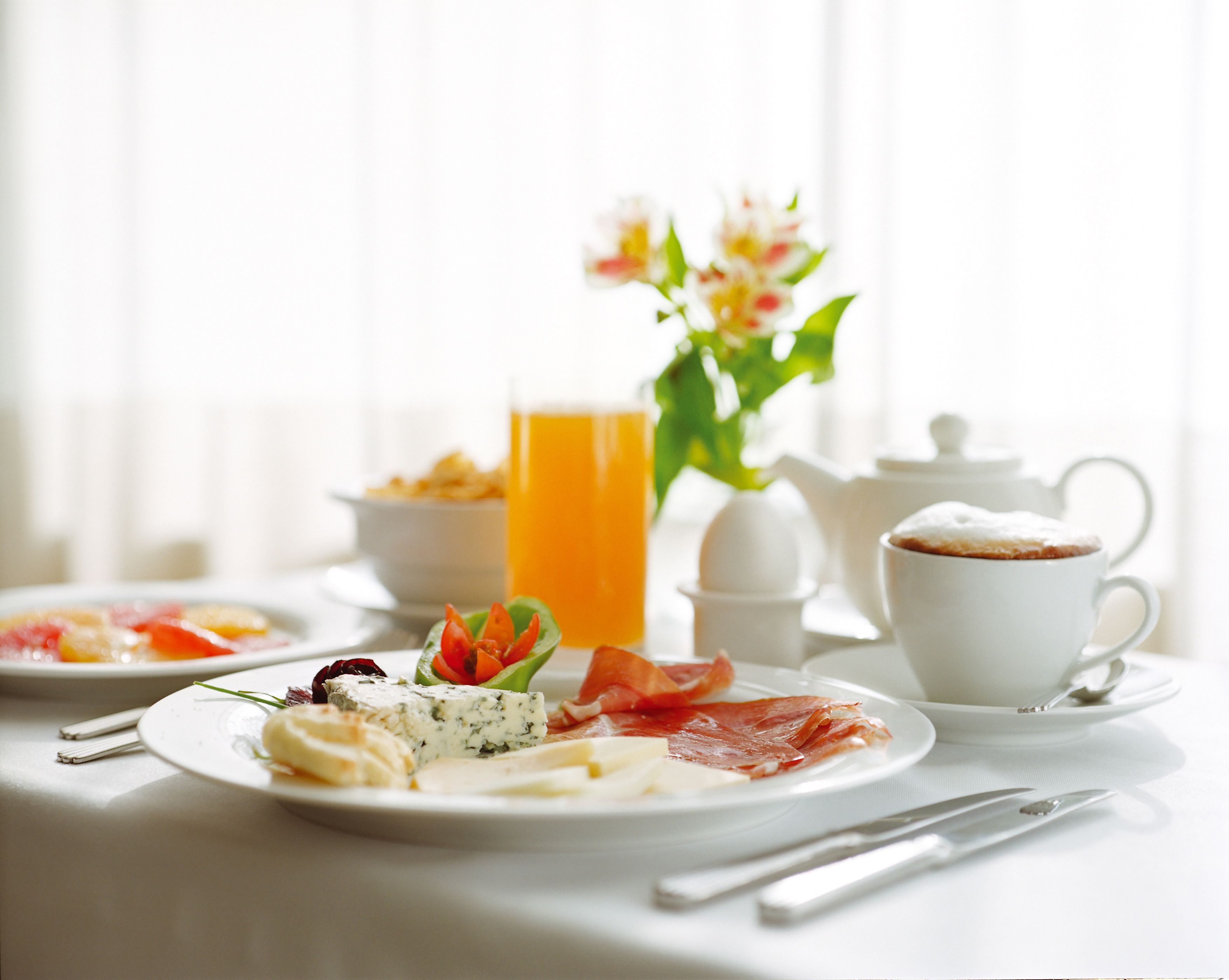 A breakfast setting with plates of food, a cup of coffee, and a glass of orange juice.