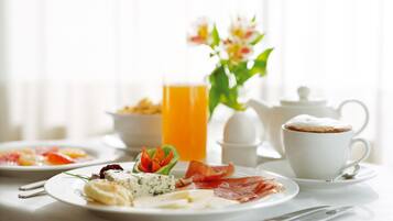 A breakfast setting with plates of food, a cup of coffee, and a glass of orange juice.