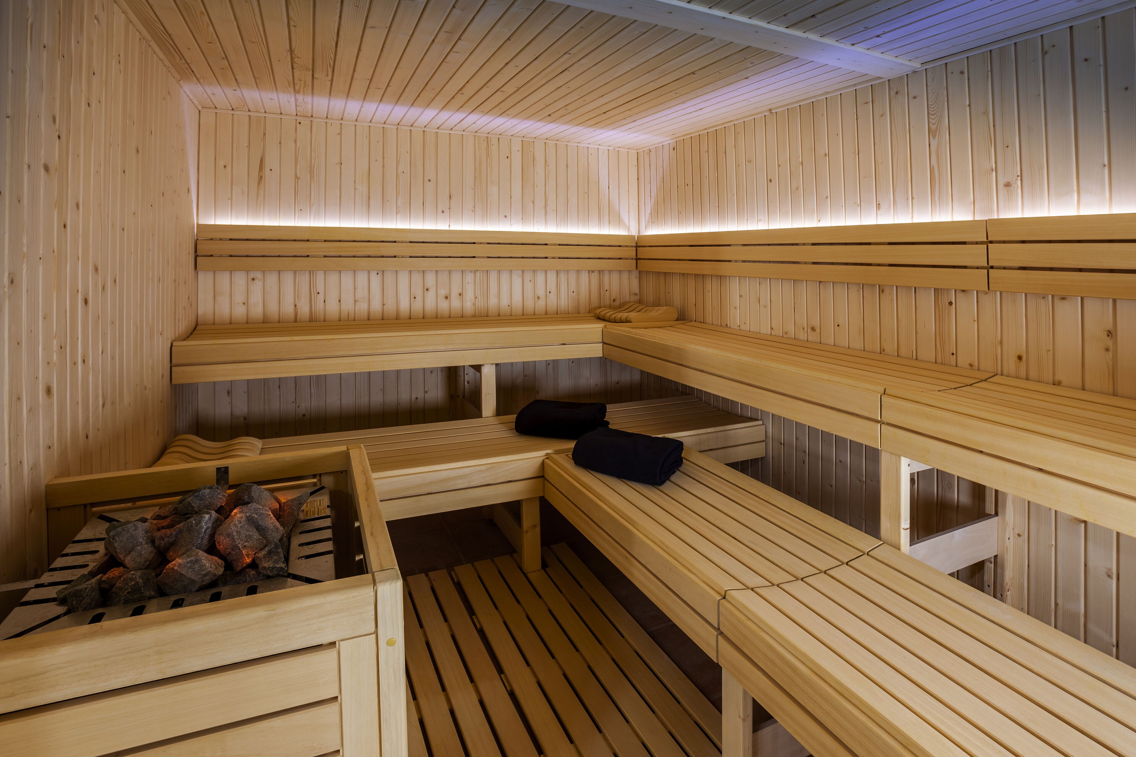 Una sauna con bancos de madera, algunos con toallas.