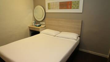 A hotel room with a bed, a bedside table with a phone, a coffee maker, and a framed picture on the wall.