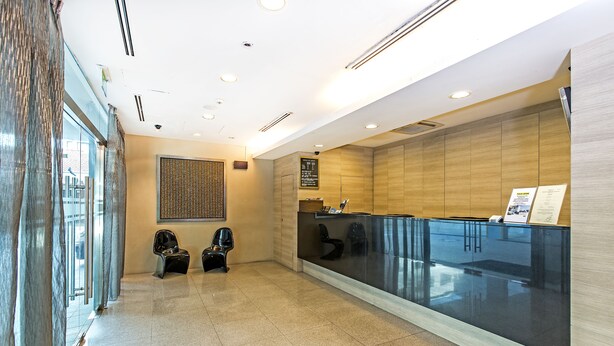 A reception area with a glass partition, a reception desk, and two black chairs. - Hotel 81 Lucky (Singapore)