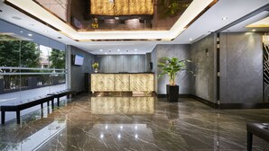 Eine moderne Lobby mit Marmorboden, einer Rezeption und einer großen Pflanze in einem Topf.