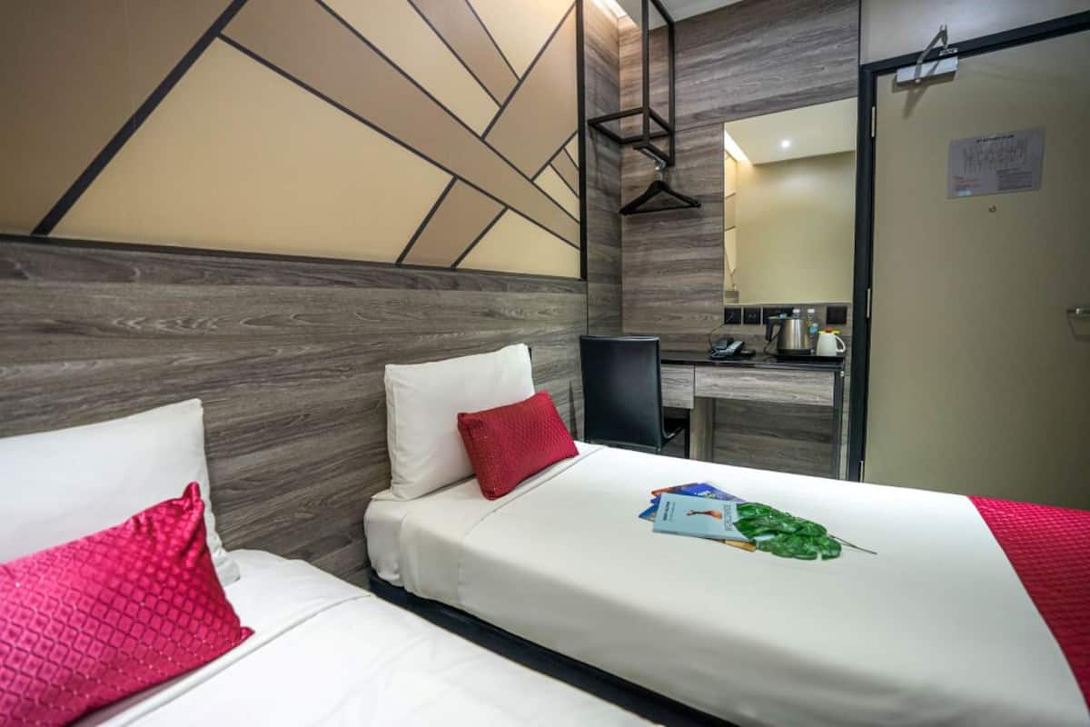 Quarto de hotel com duas camas, uma escrivaninha e um espelho.