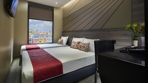 Ein Hotelzimmer mit zwei Betten, einem Schreibtisch, einem Telefon und einem Fernseher.
