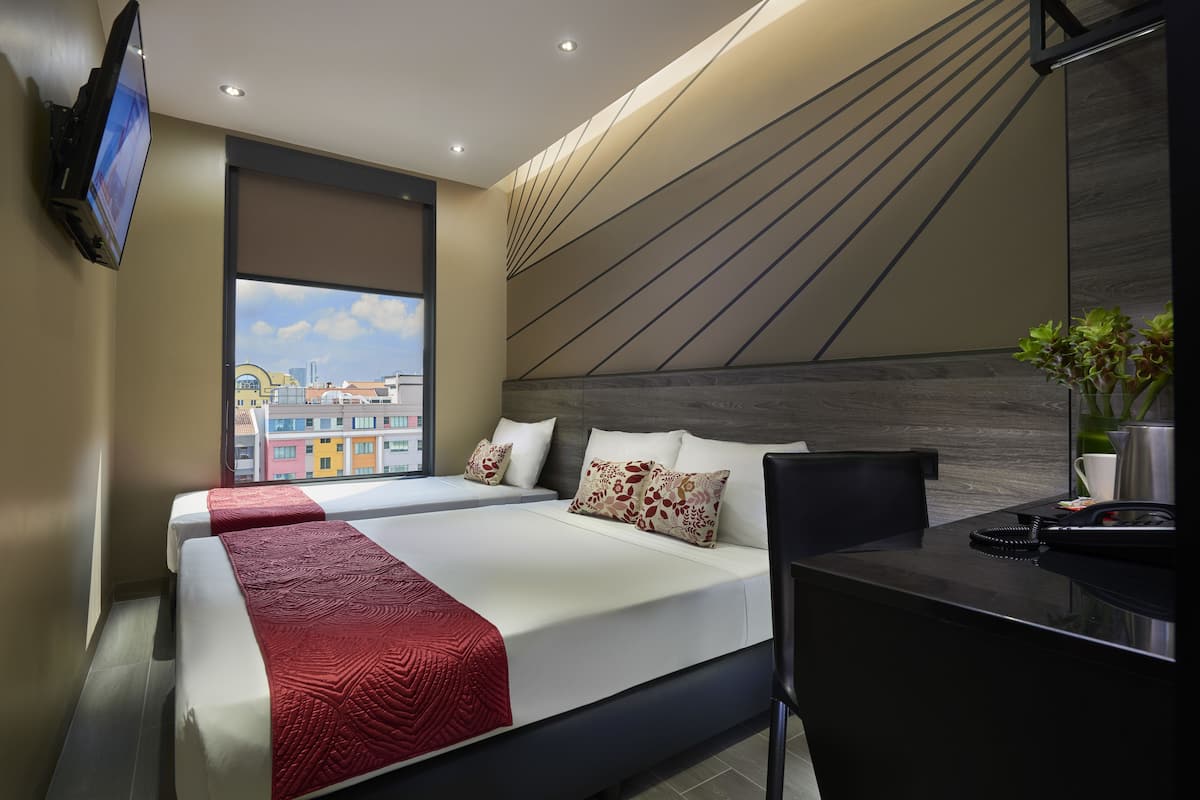 Quarto de hotel com duas camas, uma escrivaninha, telefone e televisão.