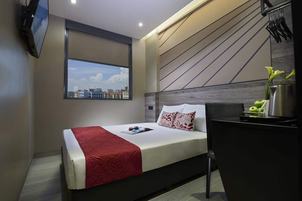 Quarto de hotel moderno com uma cama, uma escrivaninha e vista para a cidade.