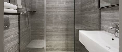 A modern bathroom with a glass-enclosed shower, a white sink, and a mirror above it.