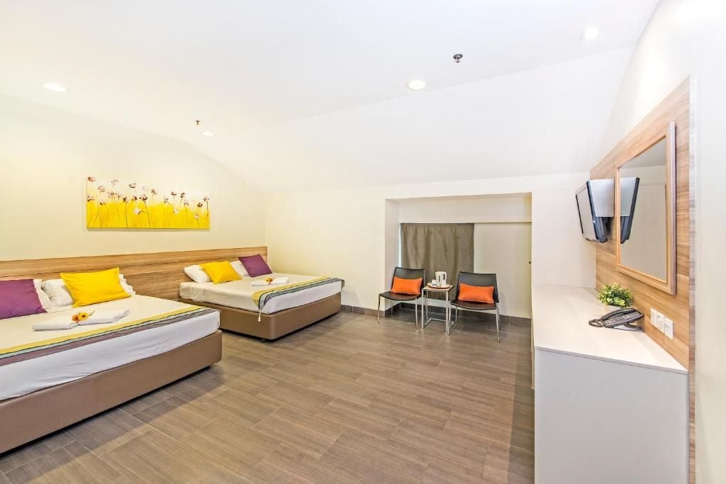 A hotel room with two beds, a desk, a chair, a telephone, and a painting on the wall.