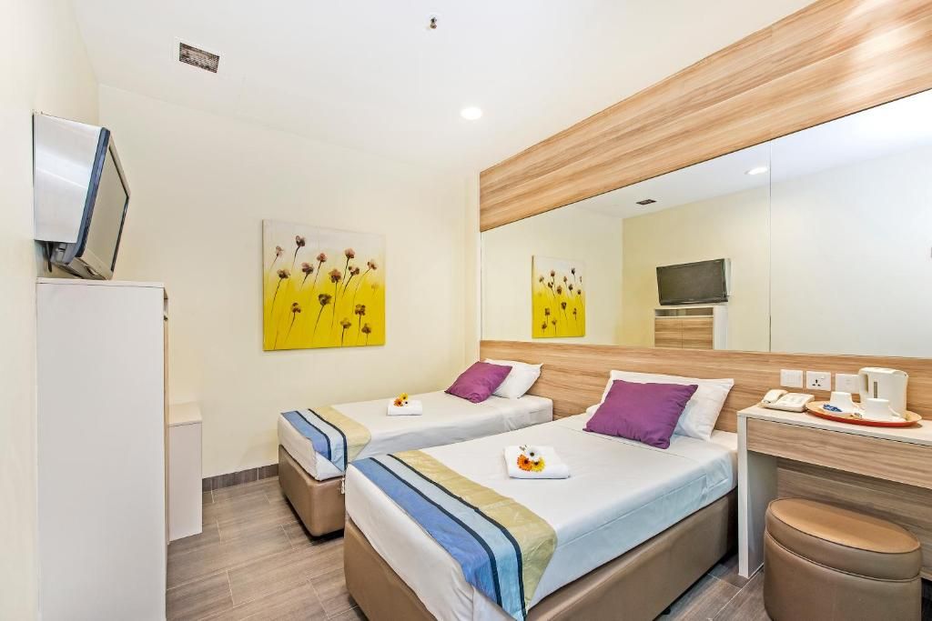 Una habitación de hotel con dos camas, un escritorio, un espejo y obras de arte en las paredes.