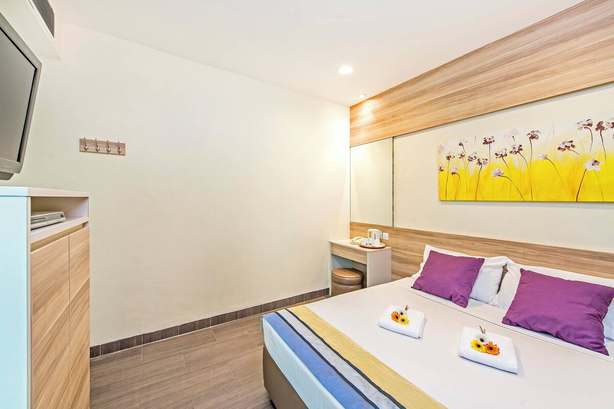 A modern hotel room with a bed, bedside table, and a painting on the wall.