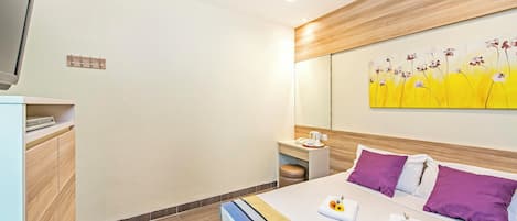 A modern hotel room with a bed, bedside table, and a painting on the wall.