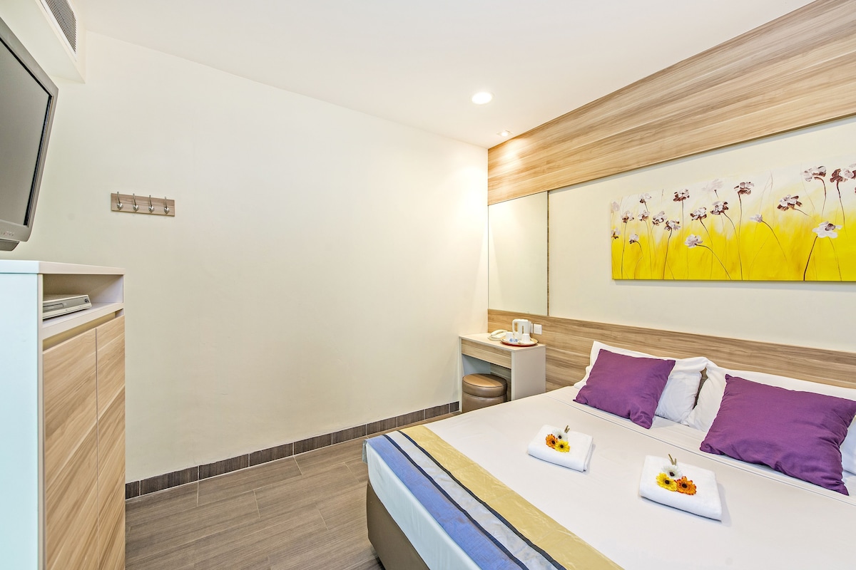 Una habitación de hotel moderna con cama, mesita de noche y un cuadro en la pared.
