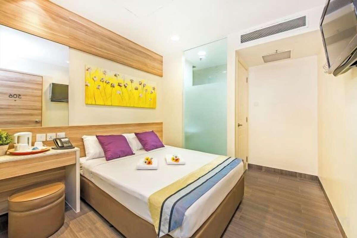 Una habitación de hotel con cama, mesita de noche y televisión.