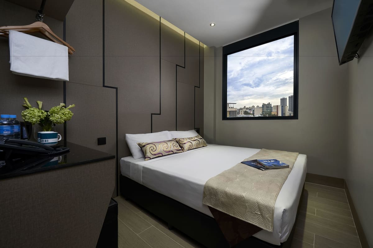 Quarto de hotel moderno com cama, escrivaninha e janela com vista para a cidade.
