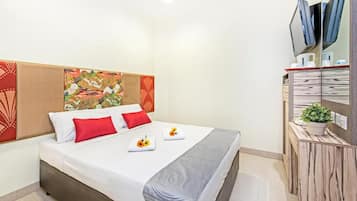 A hotel room with a bed, a bedside table with a plant, and a wall-mounted TV.