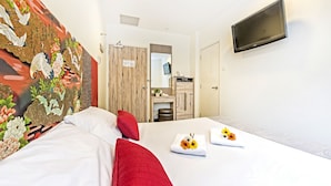 A hotel room with a bed, red pillows, a flat-screen TV, and a floral tapestry on the wall. - Hotel 81 Osaka (Singapore)