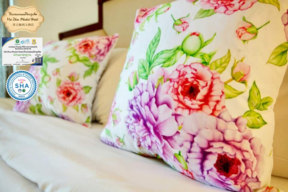 A bed with floral-patterned pillows and a certificate of safety.