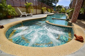 A swimming pool with a hot tub, surrounded by lounge chairs and potted plants. - Mei Zhou Phuket Hotel (Phuket)