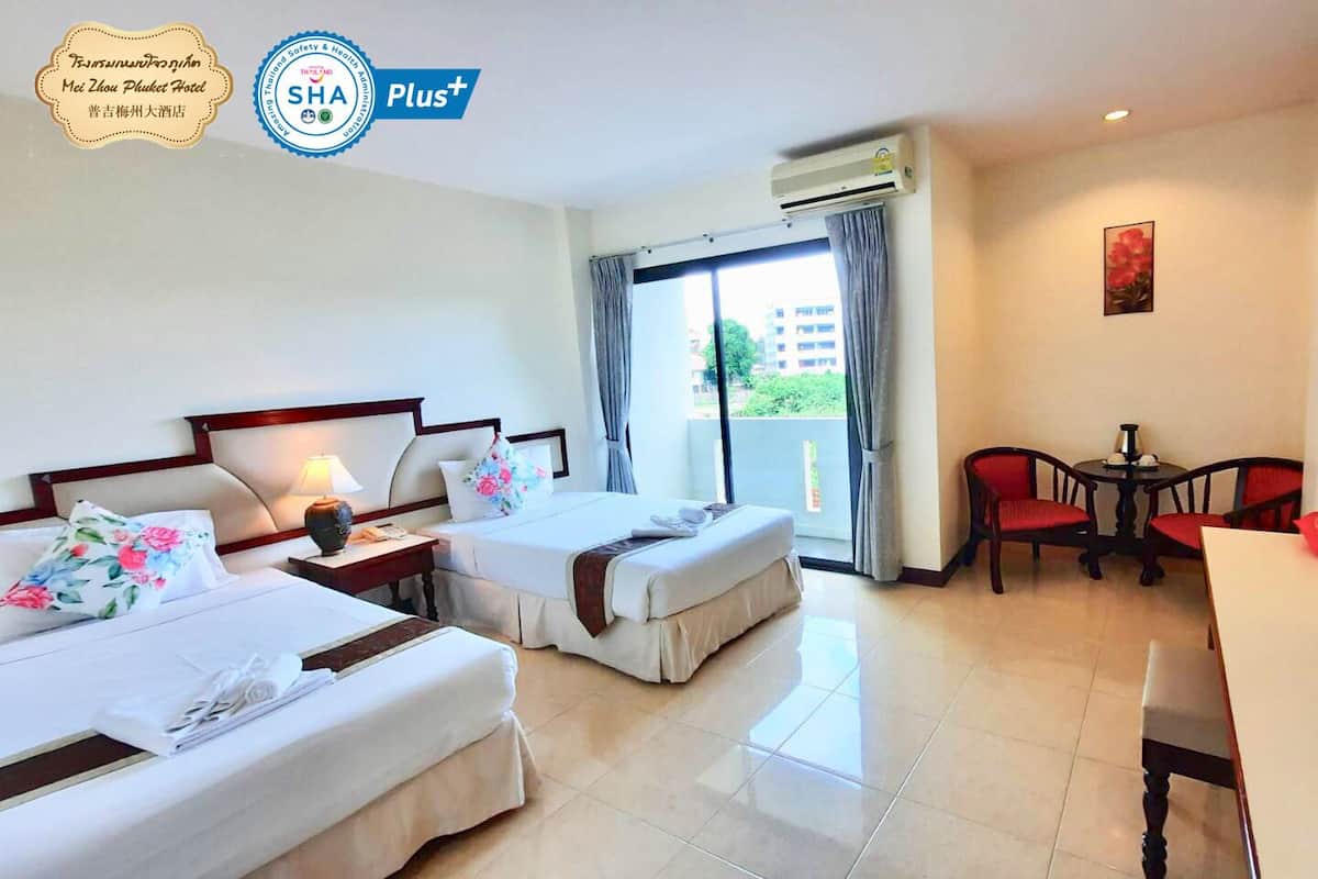 A hotel room with two beds, a desk, a chair, and a balcony with a view.