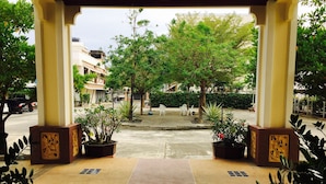 An outdoor covered walkway with potted plants and a tiled floor leading to a street. - Mei Zhou Phuket Hotel (Phuket)