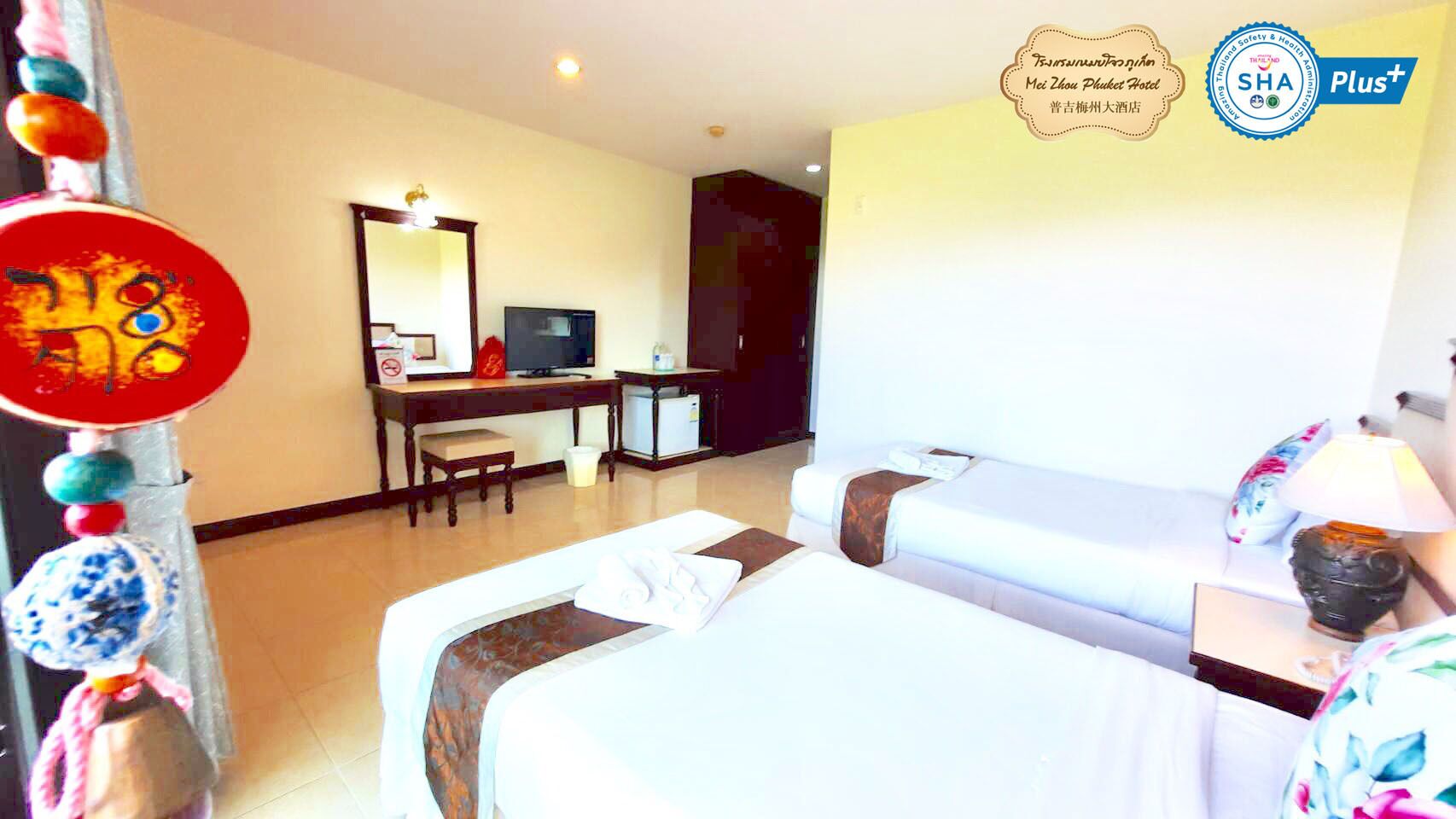A hotel room with two beds, a desk, a television, and a decorative wall hanging.