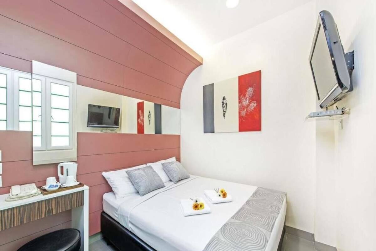 A hotel room with a bed, a desk, a chair, a TV, and artwork on the walls.