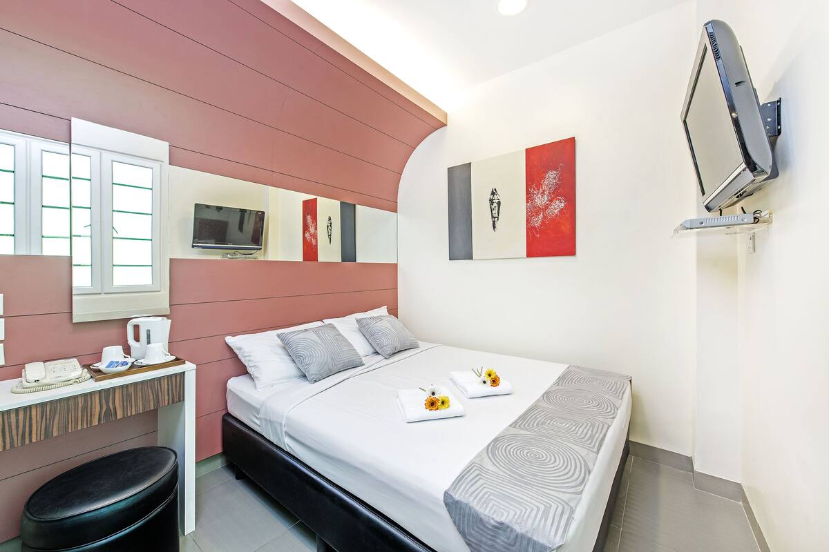 A modern hotel room with a bed, bedside table, and a desk with a telephone and coffee maker.