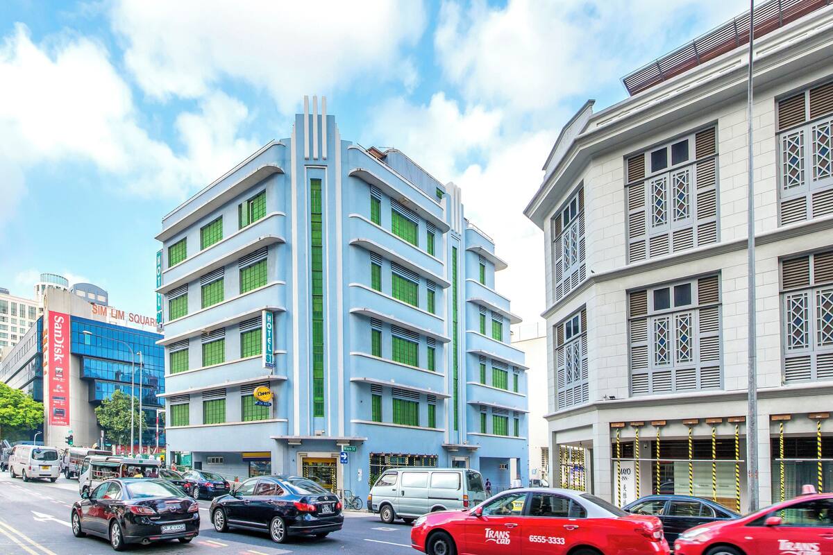 A multi-story building with a modern design, featuring a prominent blue facade and green window frames.