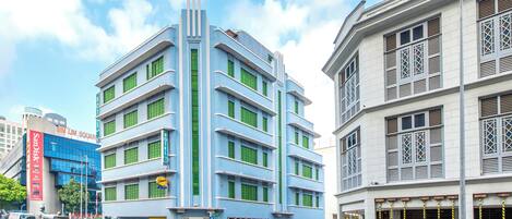 A multi-story building with a modern design, featuring a prominent blue facade and green window frames.