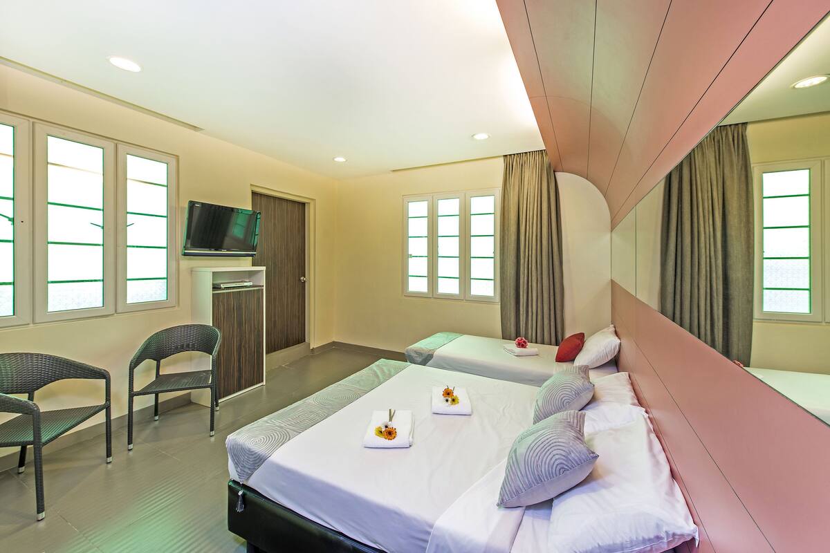 A hotel room with two beds, a TV, and a desk.