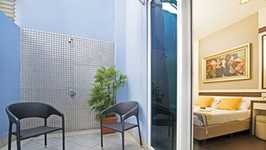 A room with a bed, a chair, a potted plant, and a glass door leading to another room. - Hotel 81 Bugis (Singapore)