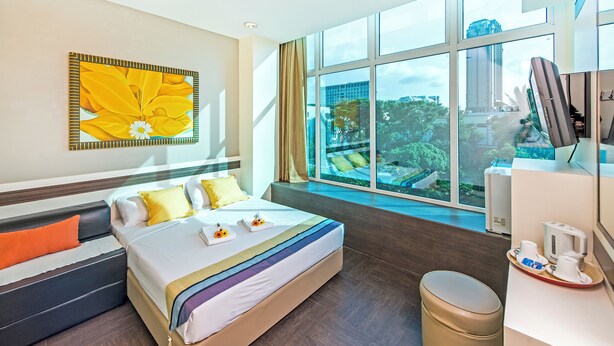 A hotel room with a large bed, a view of greenery outside, and a coffee station. - Hotel 81 Bugis (Singapore)