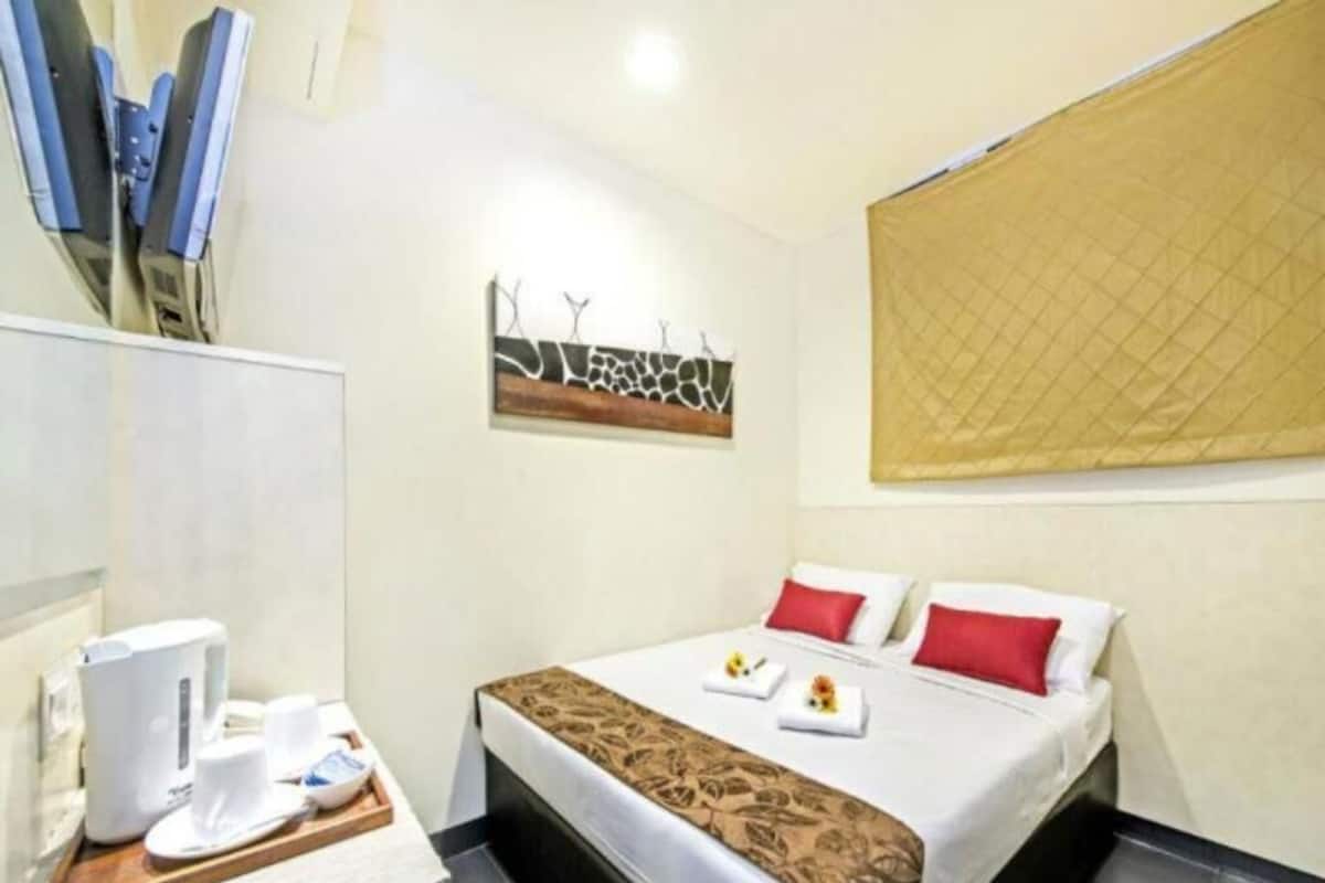 Una habitación de hotel con cama, mesita de noche con cafetera y una obra de arte colgada en la pared.
