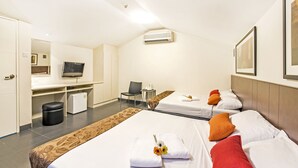 Una habitación de hotel con dos camas, un escritorio, una silla y un televisor.