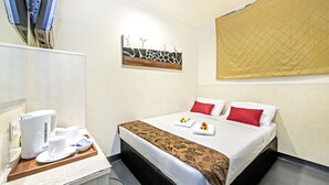 Una habitación de hotel con cama, cafetera y una bandeja con tazas y un plato.