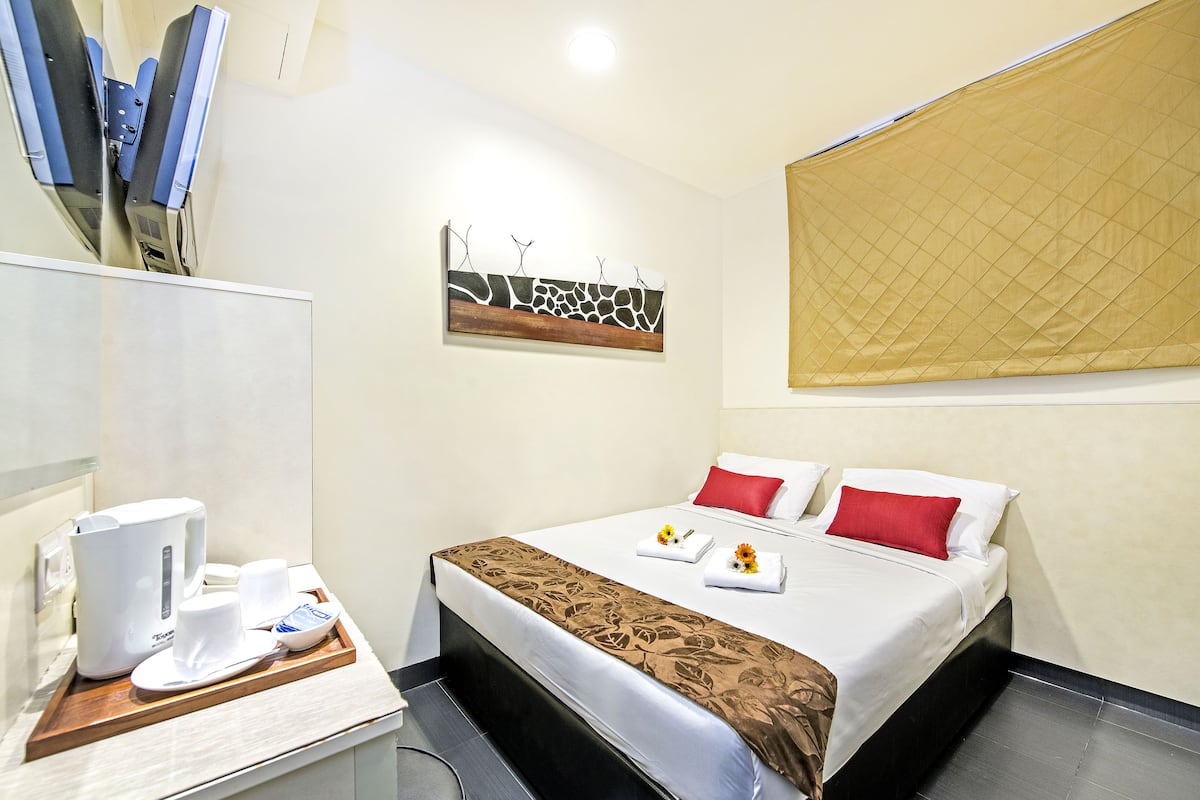 Una habitación de hotel con cama, cafetera y una bandeja con tazas y un plato.
