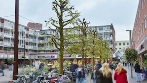 A street scene with bicycles parked along the sidewalk, pedestrians, and buildings with various storefronts. - Holiday Inn Express Amsterdam - Schiphol by IHG (Hoofddorp)