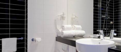 A modern bathroom with a white toilet, a sink with a mirror above, and a shower area.