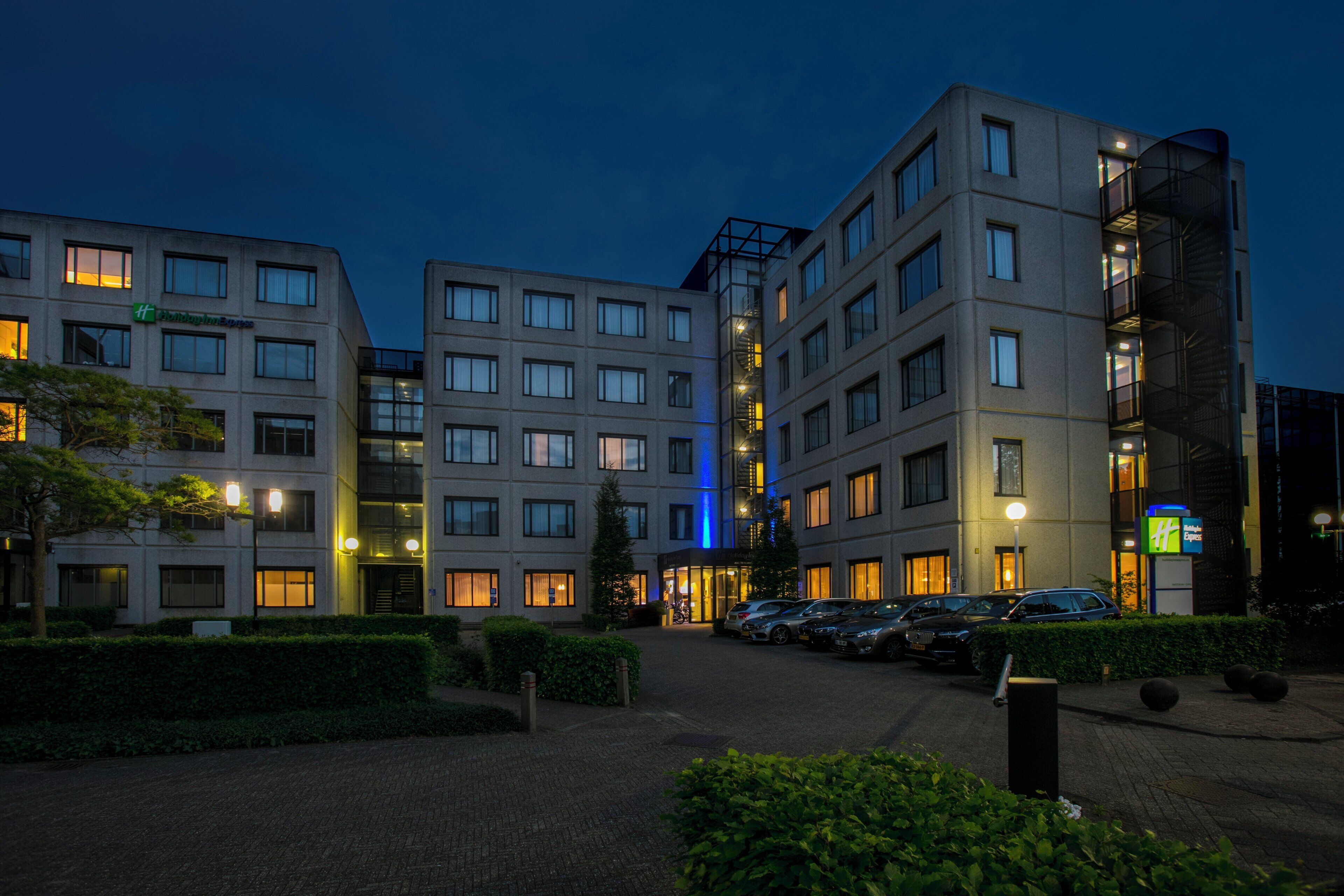 Un hôtel moderne à plusieurs étages, doté d’un parking et d’une entrée bien éclairée.